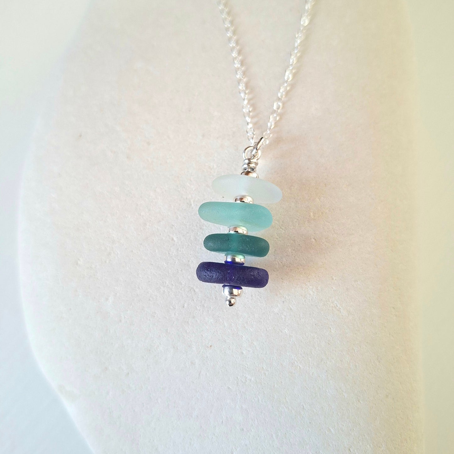 Silver necklace with a pendant made with 4 pieces of sea glass in shades of blue.