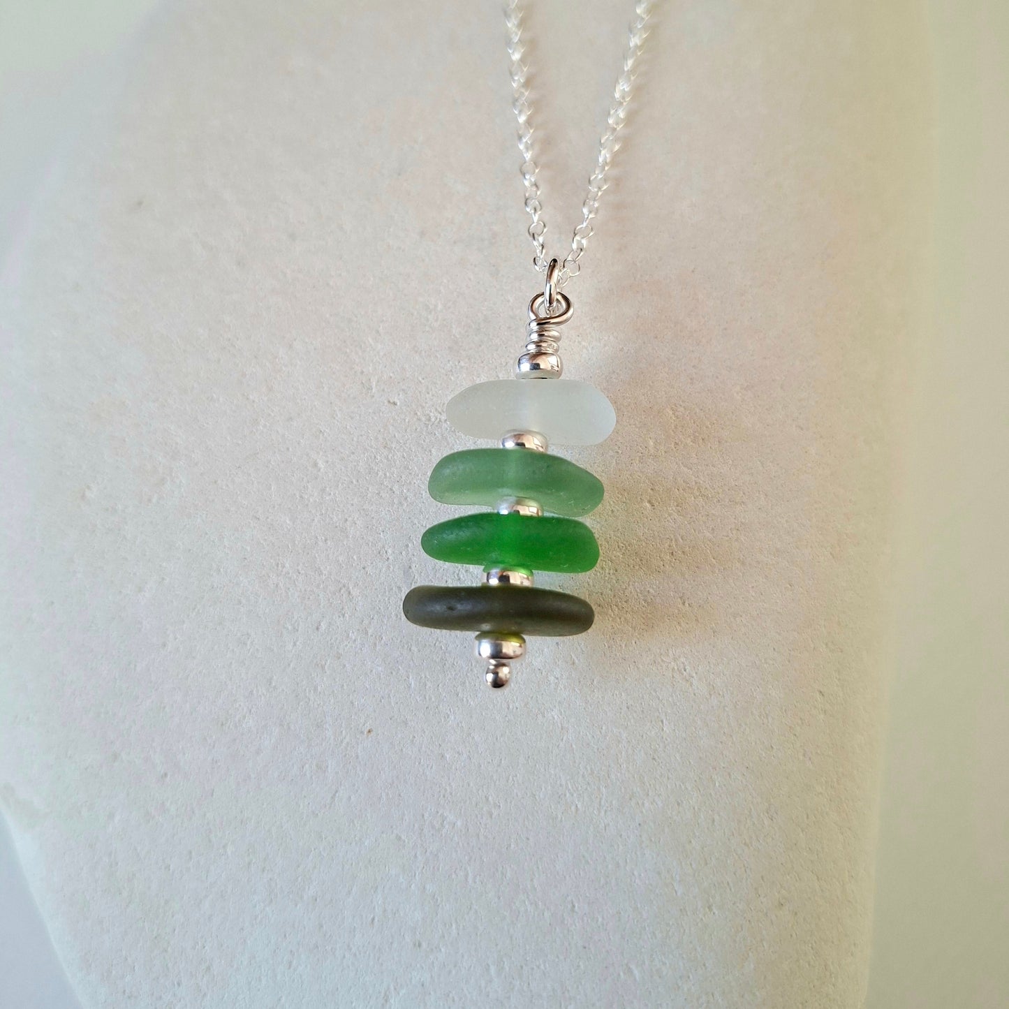 Silver necklace with a pendant made with 4 pieces of sea glass in shades of green.