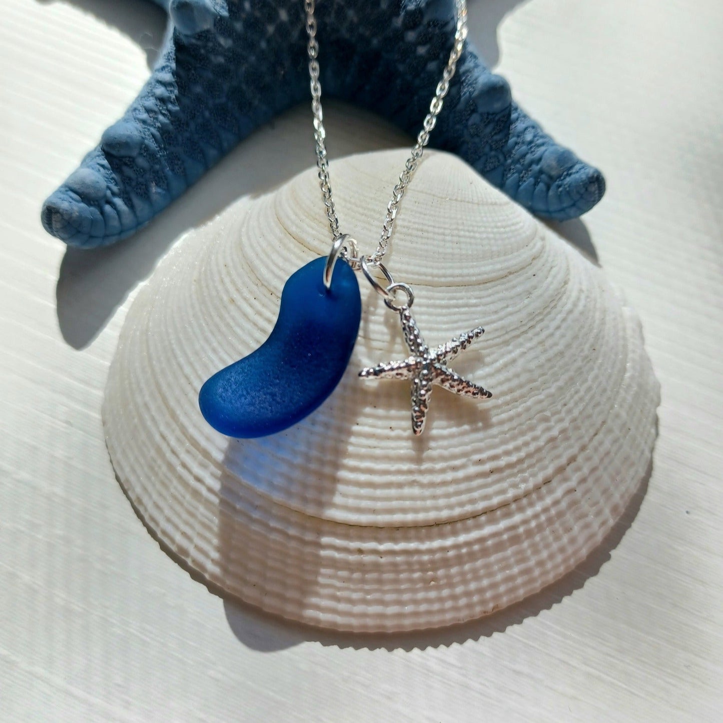 Silver necklace with a cobalt blue sea glass pendant and starfish charm.