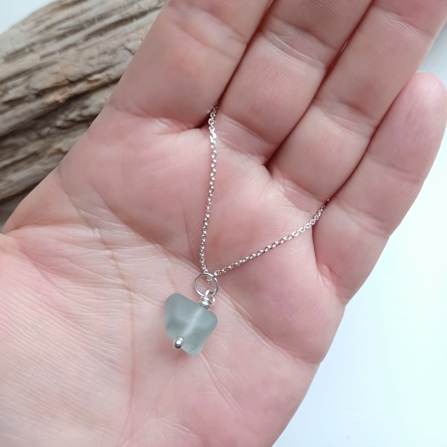 A pendant made of sea foam colour sea glass on a silver chain necklace.