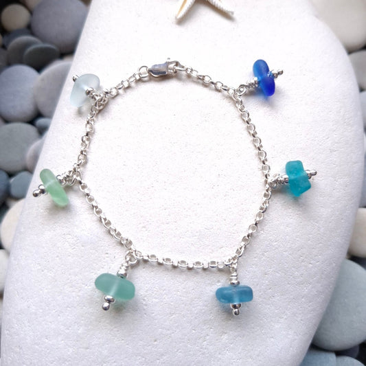 A silver chain bracelet with five small sea glass jewels in various coastal colours.