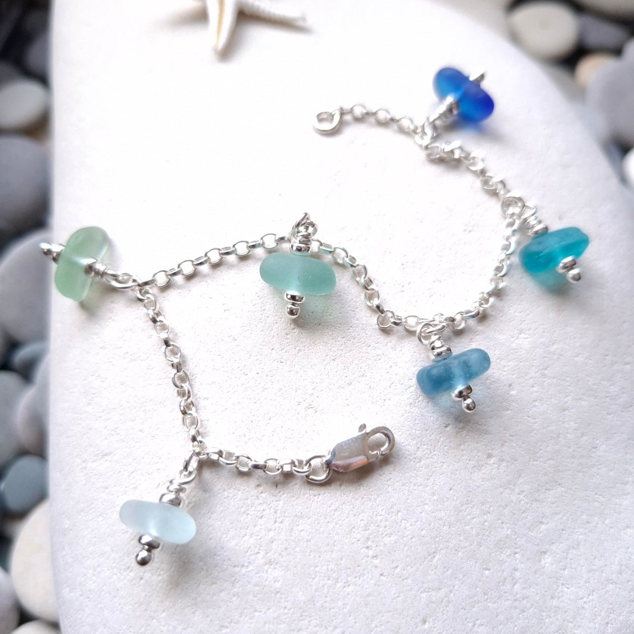 A silver chain bracelet with five small sea glass jewels in various coastal colours.