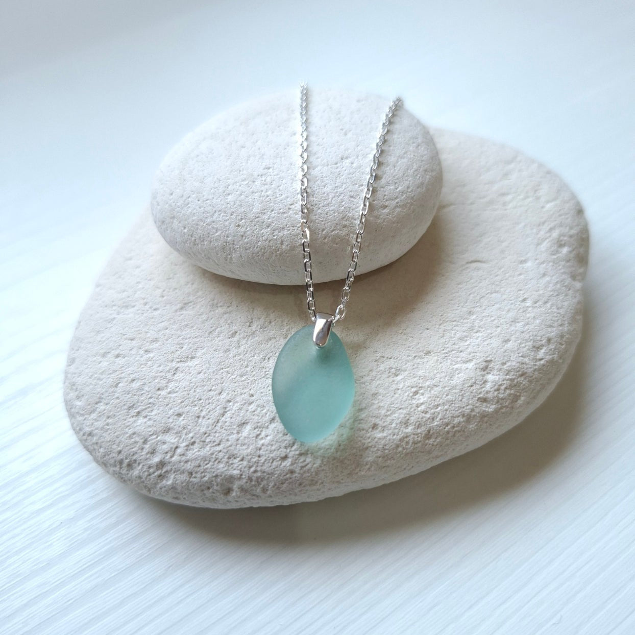 A silver chain necklace with an aqua sea glass pendant.