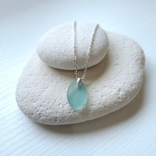 A silver chain necklace with an aqua sea glass pendant.
