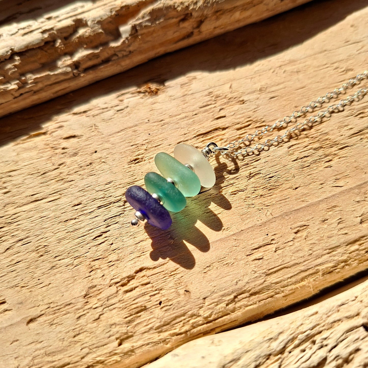 Silver necklace with a pendant made with 4 pieces of sea glass in shades of blue.