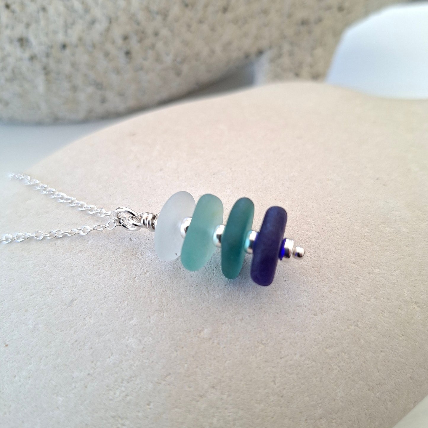 Silver necklace with a pendant made with 4 pieces of sea glass in shades of blue.