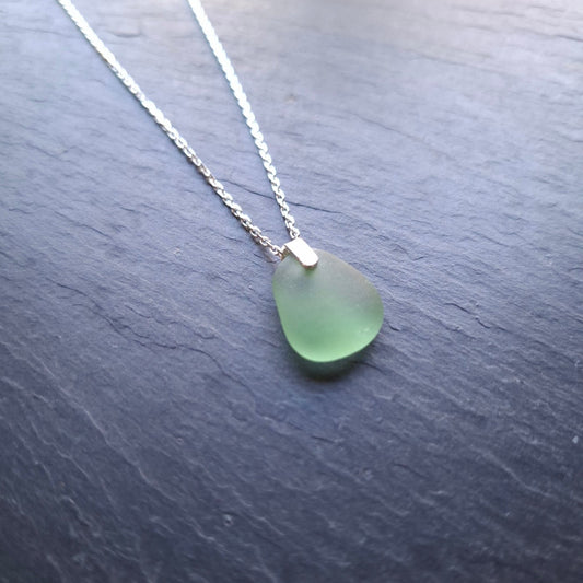 A delicate silver chain necklace featuring a light green sea glass pendant.