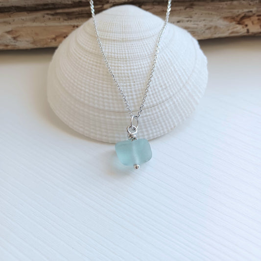 A pendant made of sea foam colour sea glass on a silver chain necklace.