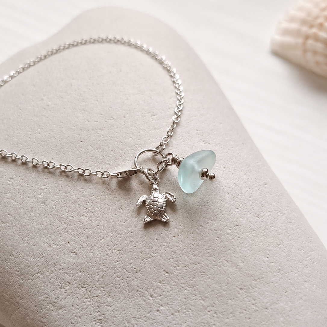 A delicate silver anklet with a sea foam sea glass charm and a silver turtle charm.