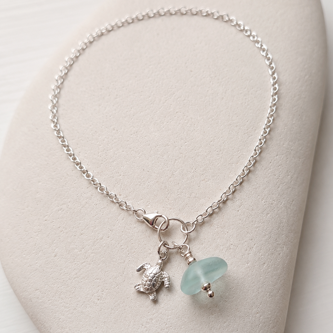 A delicate silver ankle chain with a sea foam sea glass charm and a silver turtle charm.