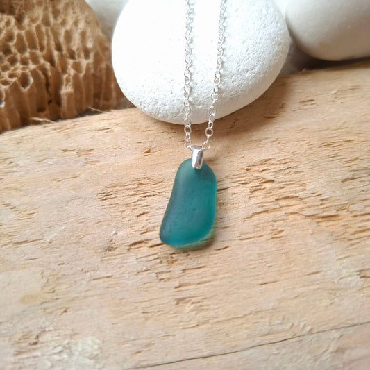 A teal sea glass pendant necklace on a sterling silver chain.