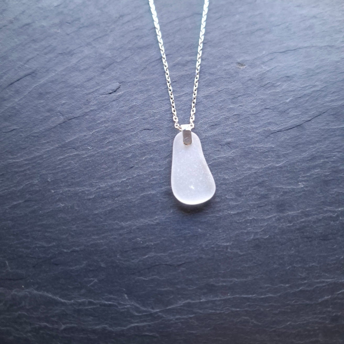 A delicate silver chain necklace featuring a white sea glass pendant.