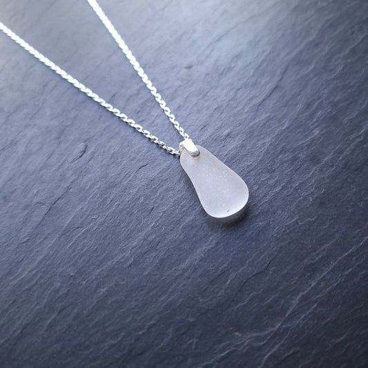A delicate silver chain necklace featuring a white sea glass pendant.