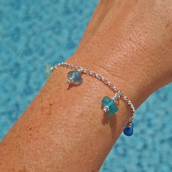 A silver chain bracelet with five small sea glass jewels in various coastal colours.