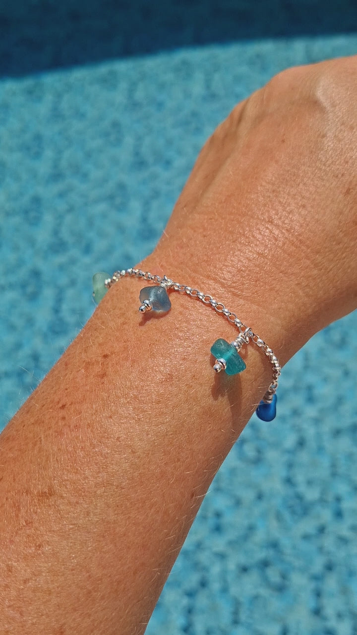 A silver chain bracelet with five small sea glass jewels in various coastal colours.